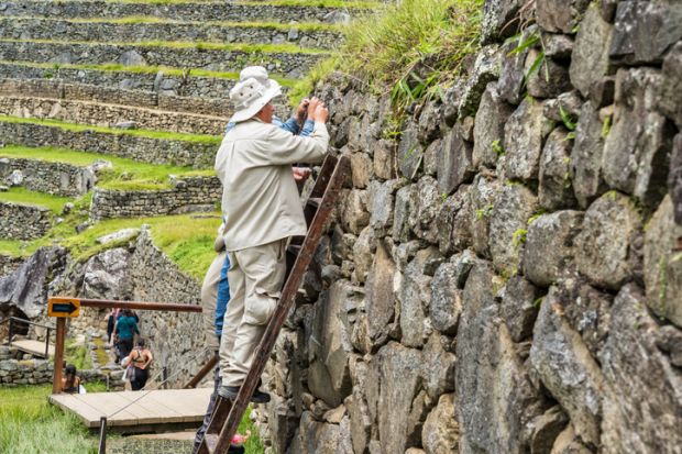 Conservation workers performing maintenance on the stone terrace walls at the Historic Sanctuary of Machu Picchu