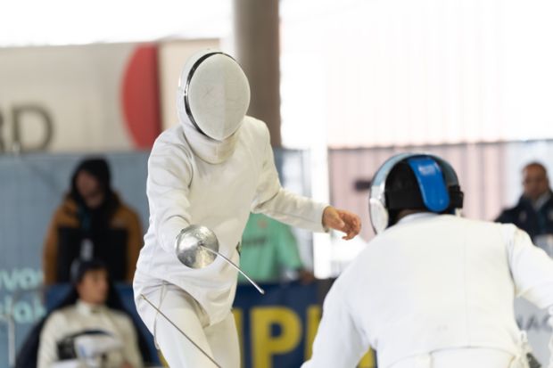Fencers in protective gear competing