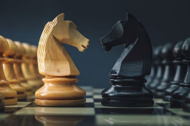 A black and white pair of chess knights face each other