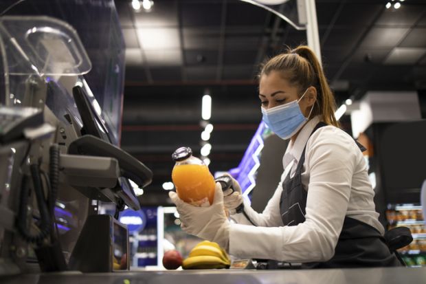 A checkout worker wearing a mask