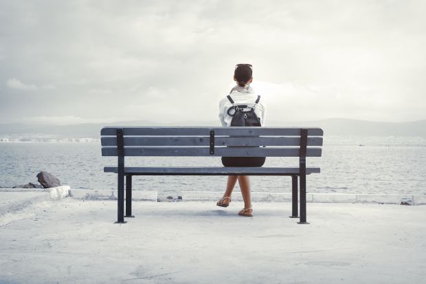 Woman sits alone on a bench illustrating the isolating experience of transitioning from academia into industry
