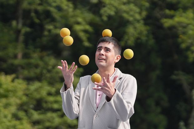 Man juggling several balls, illustrating the struggle to balance the competing pressures of teaching and studying for PhD studentships.