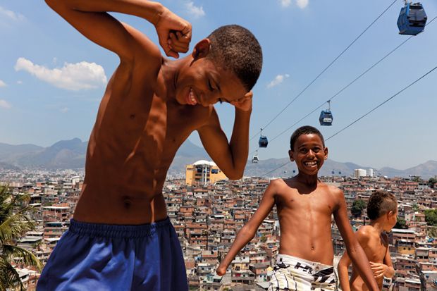 Children play near cable cars that cross over Complexo do Alemao in Rio de Janeiro, Brazil Children play near cable cars that cross over Complexo do Alemao in Rio de Janeiro, Brazil