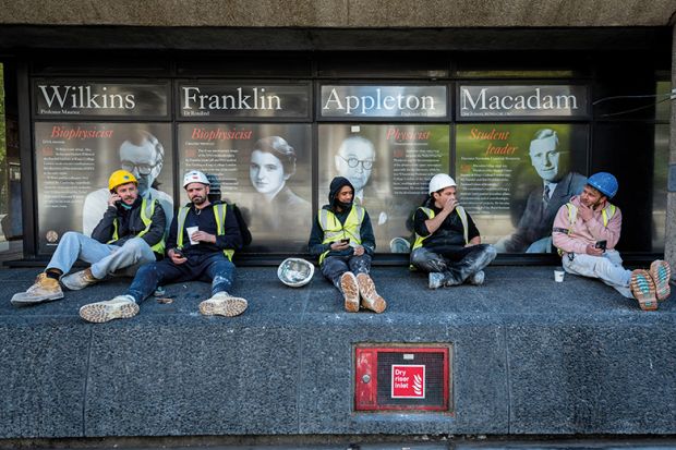 Workmen sit on a wall outside King’s College London