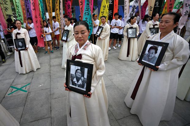 Protesters carry portraits of Korean women who were made sex slaves during Second World War