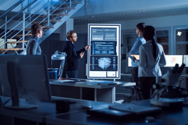 People in a lab meeting look at screens