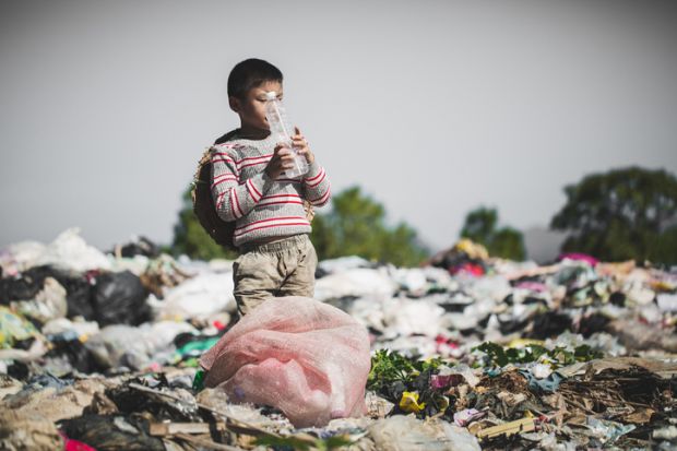 A poor boy finds a plastic bottle in a landfill site
