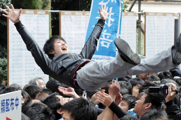 Laughing student being thrown in air by friends