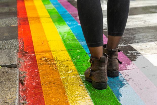 Feet walking on a rainbow road crossing