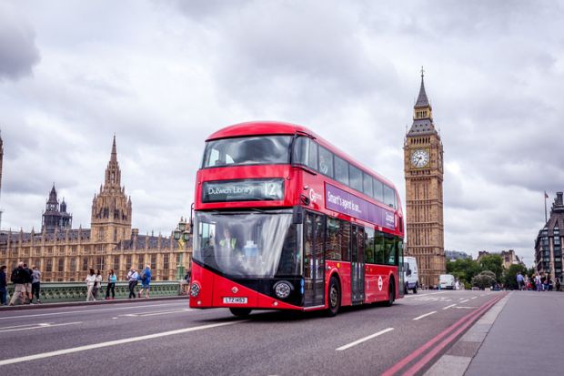 London, UK - July 8, 2015 Double-decker and the Big Ben in London. The bus is driving across the Westminster bridge with people walking in the background.