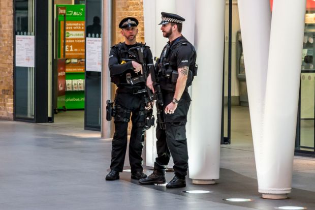 London, UK - October 31, 2015 Two police officers armed with sub-machine guns and handguns keep watch at Kings Cross rail station in central London.