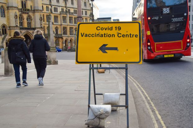 London, United Kingdom - March 19 2021 People walk past a Covid-19 Vaccination Centre sign outside Westminster Abbey.