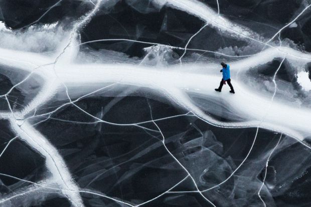 Lone man walking on cracked ice