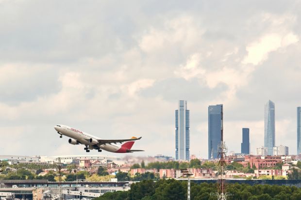 Madrid, Spain; 09-25-2021 Side view of an Airbus A330 aircraft of the Spanish airline Iberia during the take-off maneuve at Madrid Barajas airport with the famous Madrid office tower