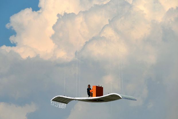 Illustration: a man plays a piano on a magic carpet obviously held up by strings