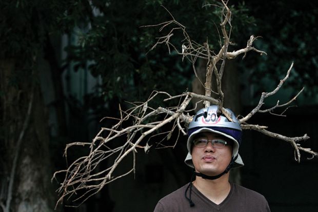 Man wears helmet with branches attached