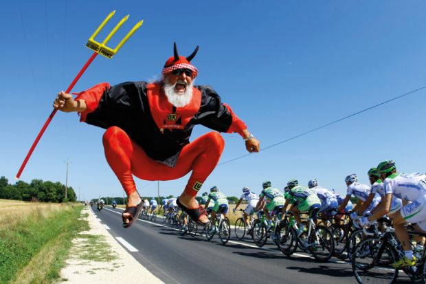 Man dressed as devil jumping beside Tour de France cycling race