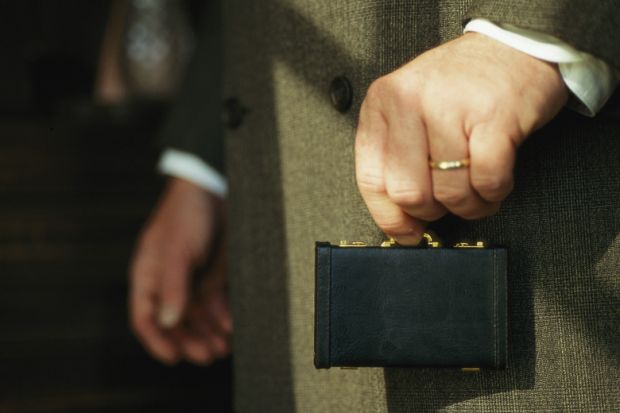 Man holding tiny briefcase between finger and thumb
