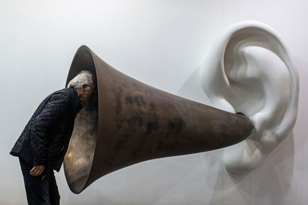 Man looking in to ear horn sculpture