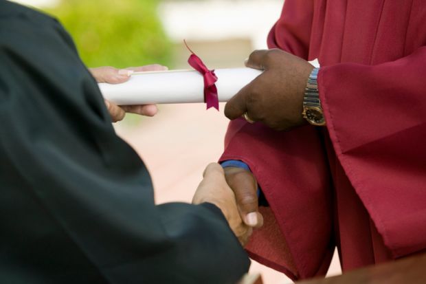 Man shaking hands and receiving university diploma