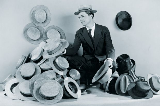 Man sitting on floor surrounded by boater hats Man sitting on floor surrounded by boater hats