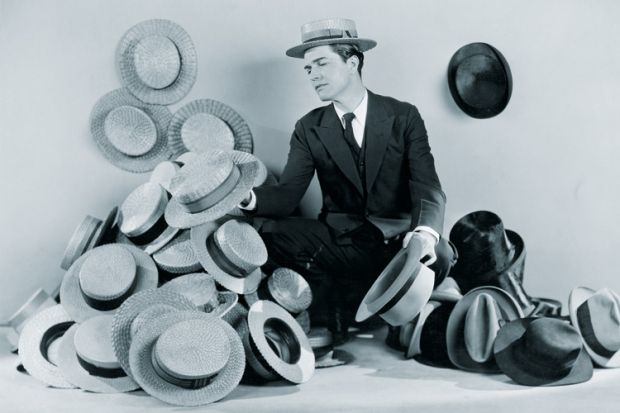 Man sitting on floor surrounded by boater hats