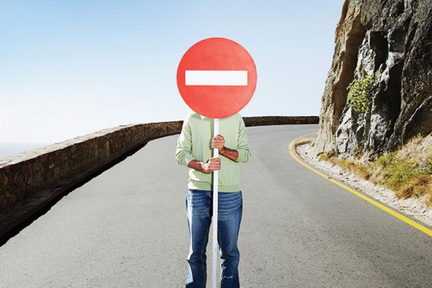 Man standing in road holding No Entry sign over face Man standing in road holding No Entry sign over face