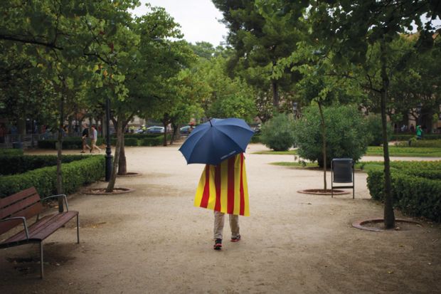 Man walks in rain wearing Catalan flag