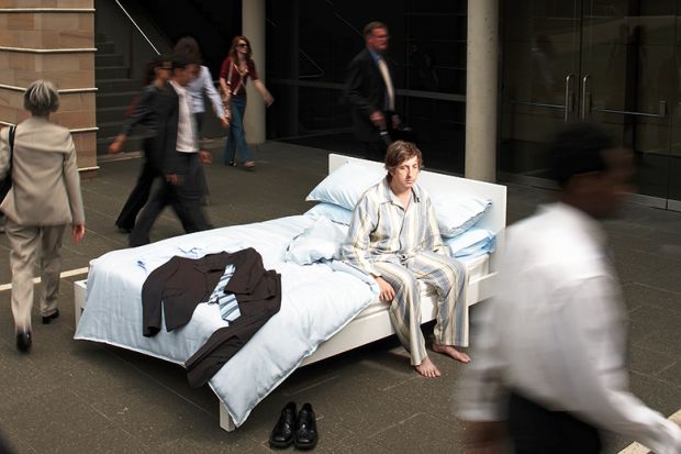 A man in pyjamas in a bed in the street