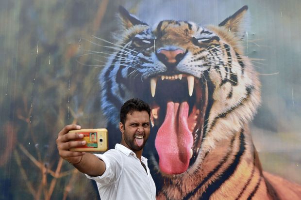 A man poses for a selfie with a tiger