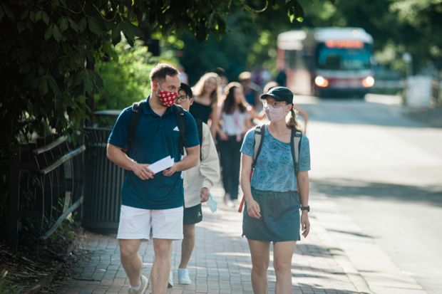 Masked students walk along Hillsborough Street on the North Carolina State University campus early Wednesday evening, August 18, 2021.