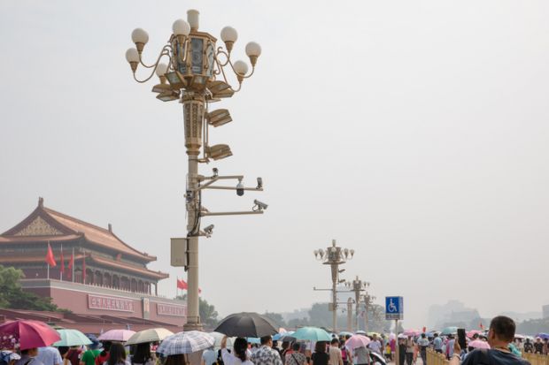  Mass tourists around the Tiananmen Gate Tower in a hot, hazy summer day in Beijing, China. Tourist attraction. Lamp post with surveillance cameras