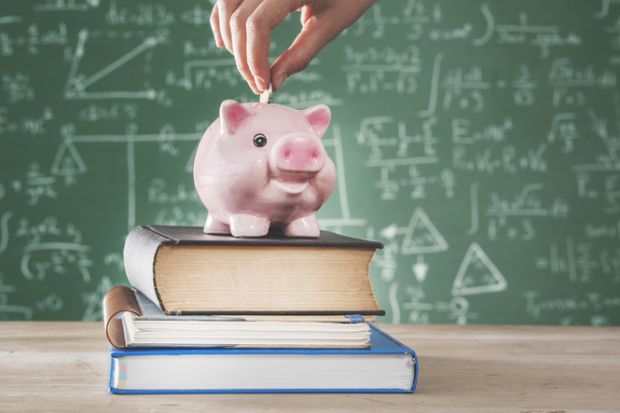 A piggy bank in front of a blackboard covered in formulas, symbolising maths funding