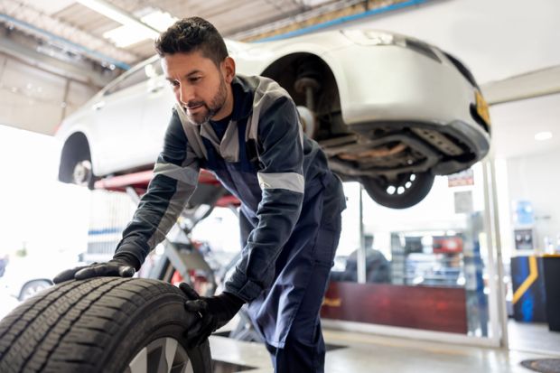 A mechanic removes the wheels of a car, symbolising the sacking of teaching staff