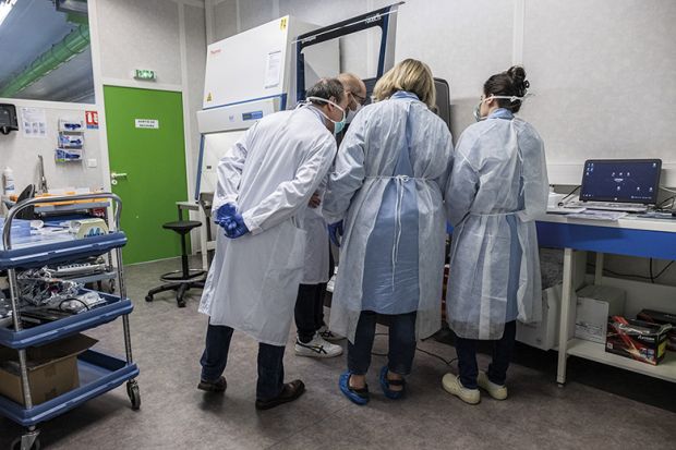 Laboratory technicians and biologists discuss testing procedures as they operate a ribonucleic acid extractor at the LBM LxBio medical biology laboratory in Rodez, France