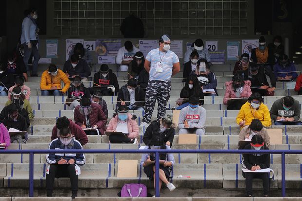 A staff member oversees students taking their UNAM admission exam while following the measures to avoid Covid-19 at Olimpico Universitario Stadium on August 19, 2020 in Mexico City,