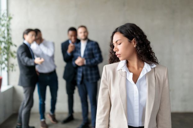 A group of men whisper behind a woman's back A group of men whisper behind a woman's back