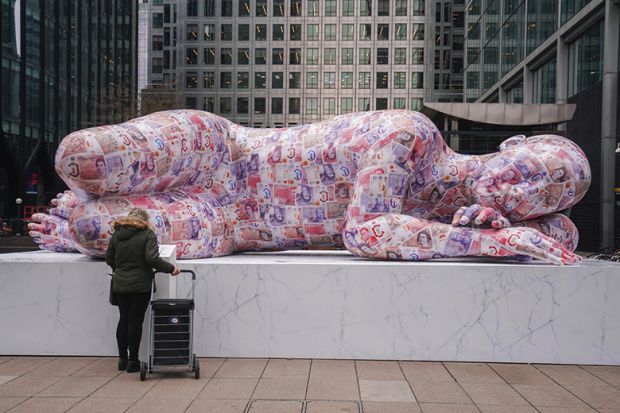 A sleeping giant sculpture made of recycled polystyrene and measuring 8 metres in length and covered in two thousands fake banknotes is installed in Canary Wharf, Docklands. To illustrate bonuses made to vice-chancellors.