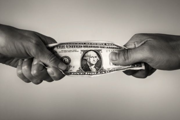 People pull on a dollar bill, illustrating competition for resources People pull on a dollar bill, illustrating competition for resources