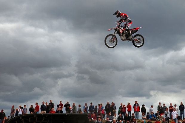 Person on a motorbike jumping above crowd of spectators. To illustrate wages rising faster at universities outside national bargaining. Person on a motorbike jumping above crowd of spectators. To illustrate wages rising faster at universities outside national bargaining.