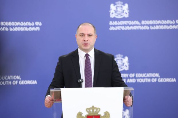 Georgia's education minister speaking at a lecturn in front of a blue backround