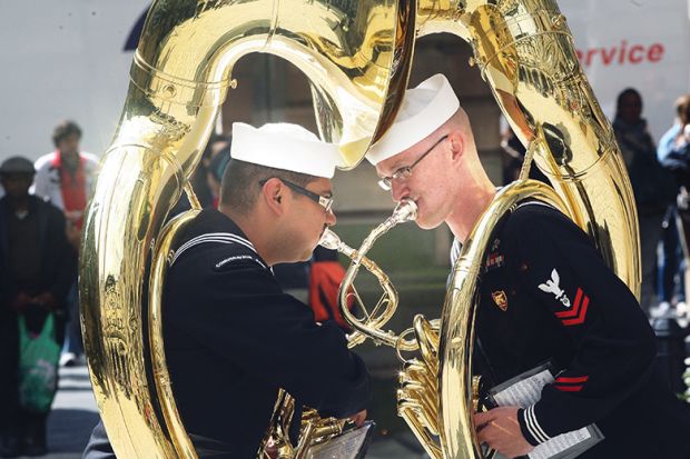 two military sousaphone players as metaphor for two sides uniting 
