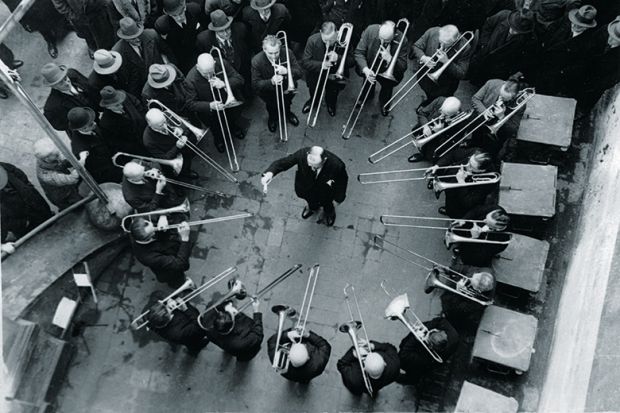 Musicians playing trombones around conductor
