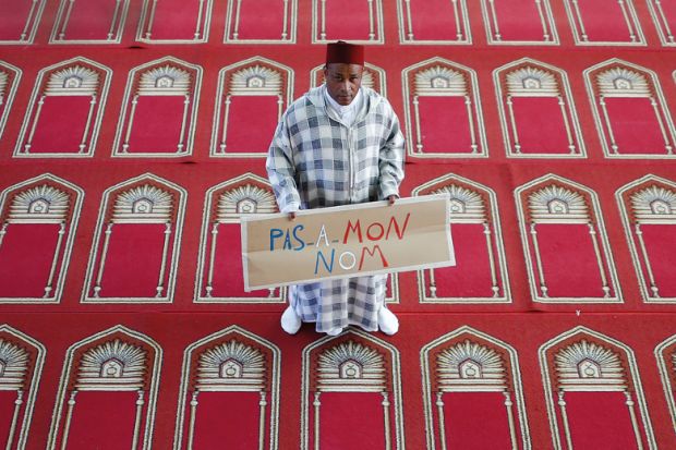 Muslim man holding "Not in my name" placard, Arrahma Mosque, Nantes, France