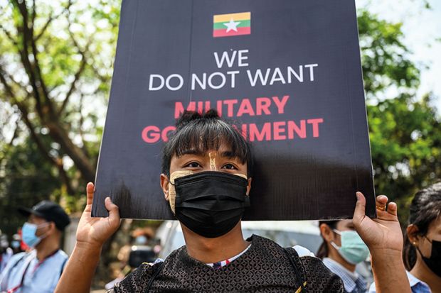 A man carries a sign during a protest next to Yangon University against the military coup in Yangon on February 25, 2021.