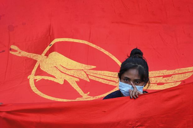 A protester stands with a Myanmar Student Union flag, 2021