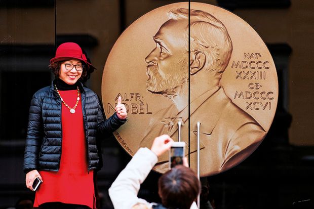 An Asian woman poses for a picture at the entrance of the Alfred Nobel Museum in Stockholm, Sweden, 2019. 