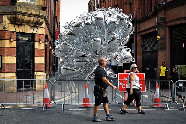 A man carries inflatable trophies on the streets of Manchester