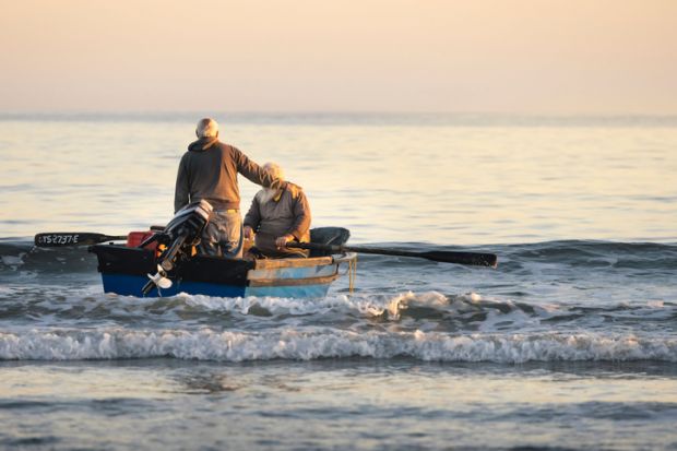 Paternoster, South Africa – May 07, 2022 Two fishermen rowing out to sea to catch fish.