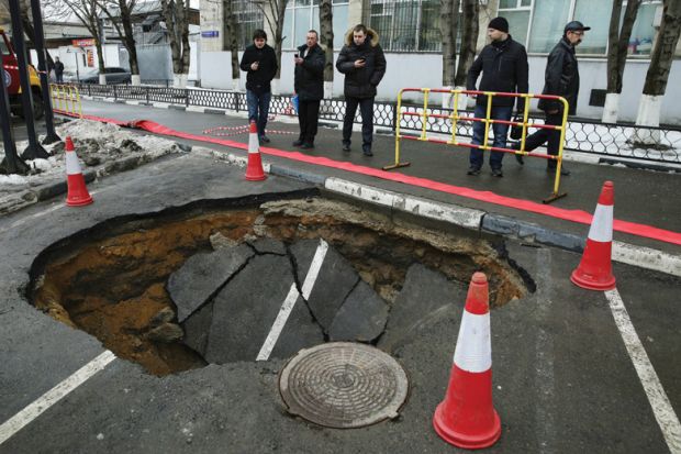 People looking at sinkhole in road